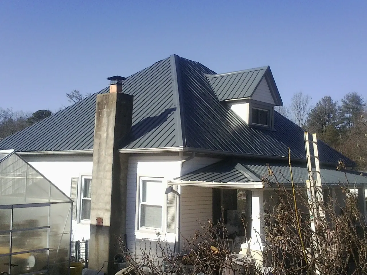 Dark blue standing seam metal roof on a white farmhouse with dormer — Slate & Tile Roof Repair by Roofing Brothers in Stony Point