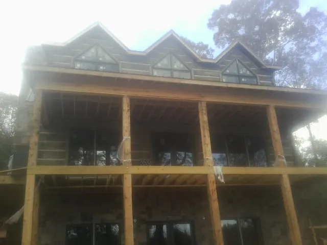 Dormers and porch framing on a large log home under construction — Roof Coating work by our crew in Stony Point