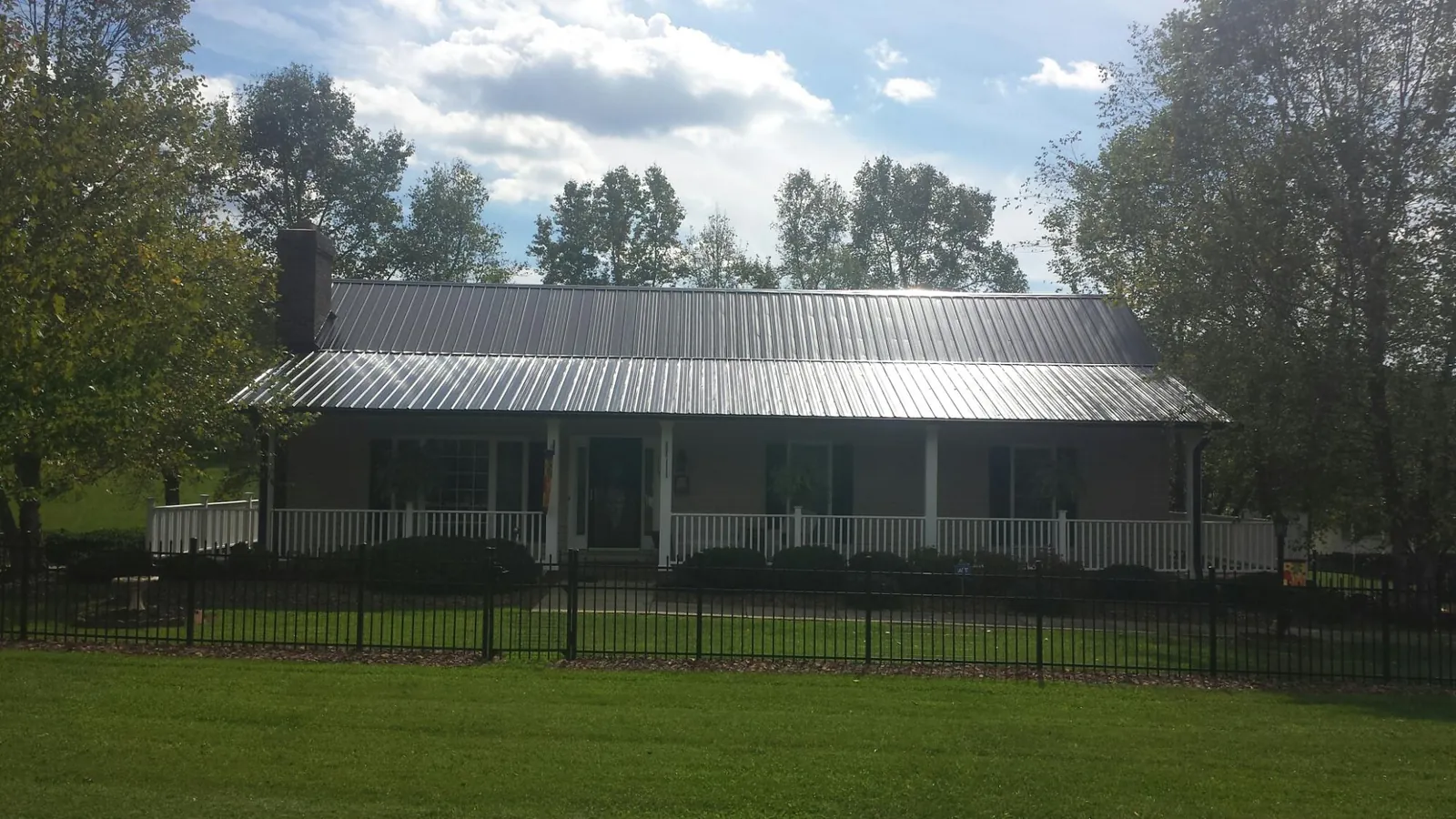 Gray metal roof on a brick ranch with a full width front porch — Gutter Guard Installation work by our crew in Stony Point