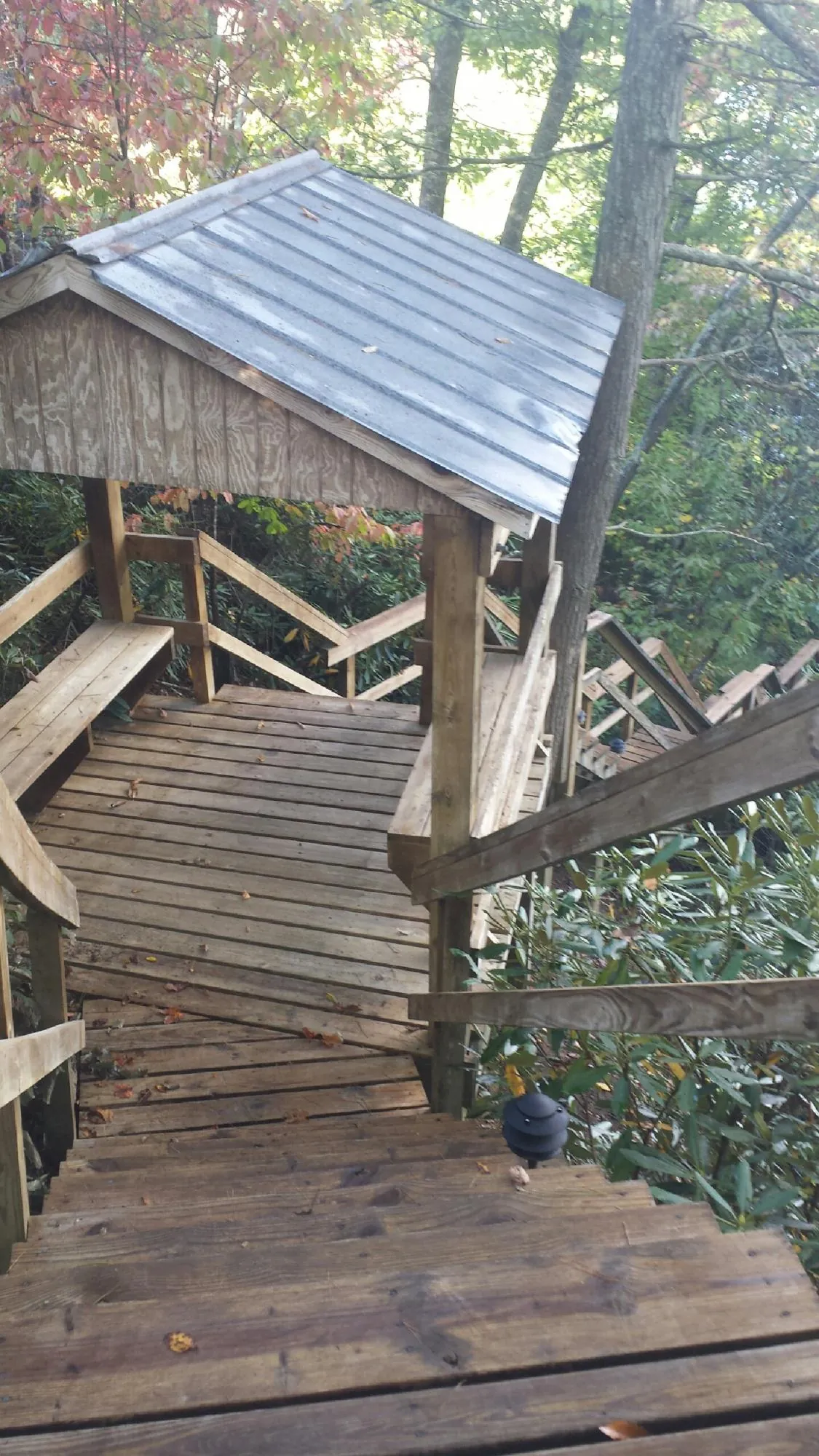 Metal roofed shelter over wooden steps on a wooded walkway — Skylight Repair & Installation work by our crew in Stony Point