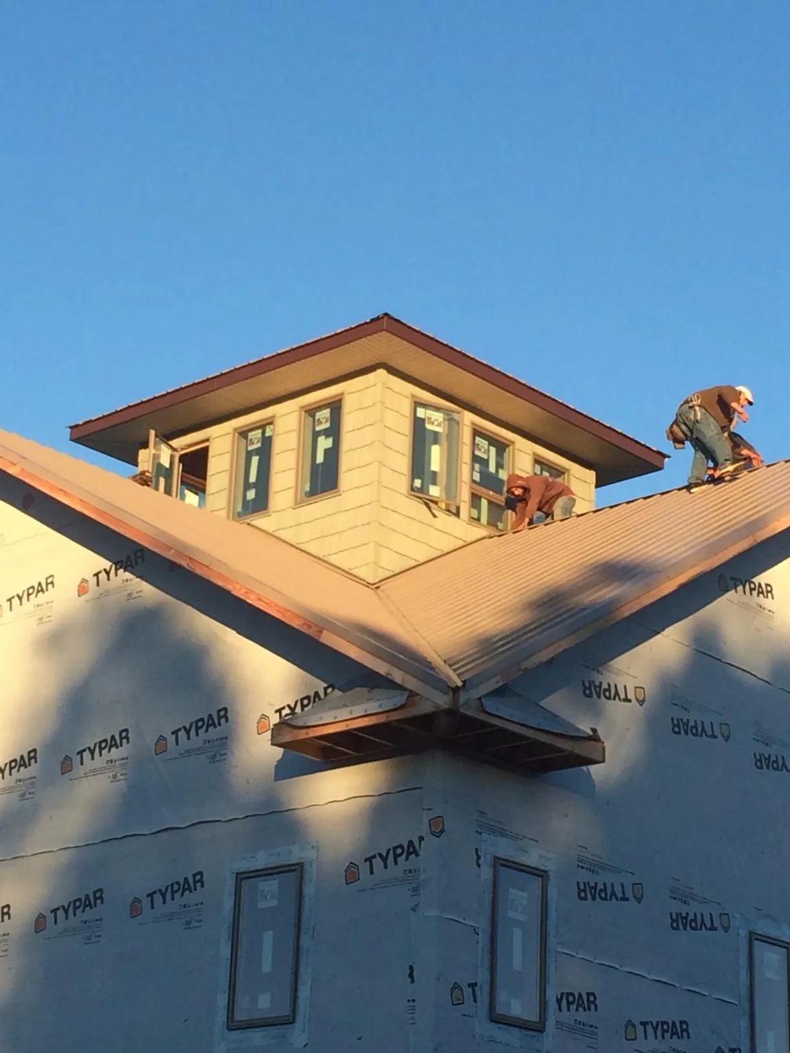 Roofers working around a rooftop cupola on a new metal roof at sunset — Roof Waterproofing in Stony Point by Roofing Brothers
